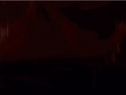 a girl with long red hair is standing in a dark room