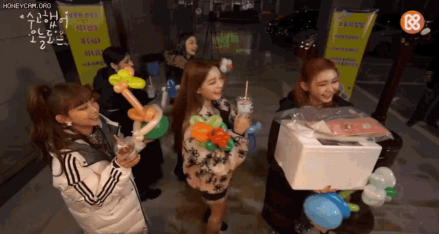 a group of girls are holding balloons in front of a sign that says ' honeycam.org '