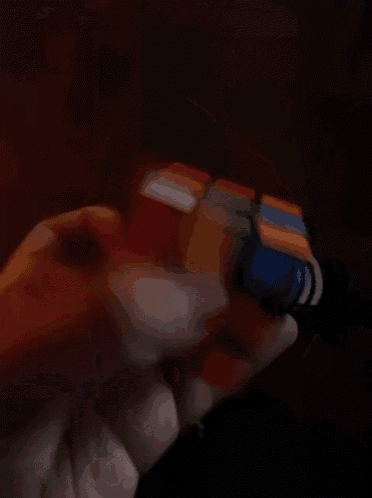 a person is holding a rubik 's cube in their hand in the dark