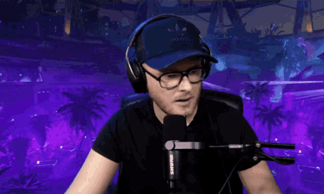 a man wearing headphones and a shure microphone stands in front of a purple background