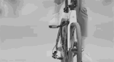 a black and white photo of a person riding a bicycle on a road .