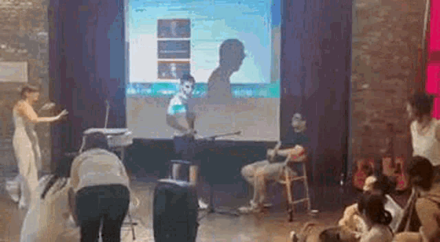 a group of people are standing around a stage in front of a large screen .