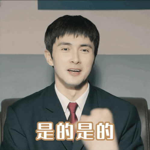 a man in a suit and tie is pointing at the camera with chinese writing above him