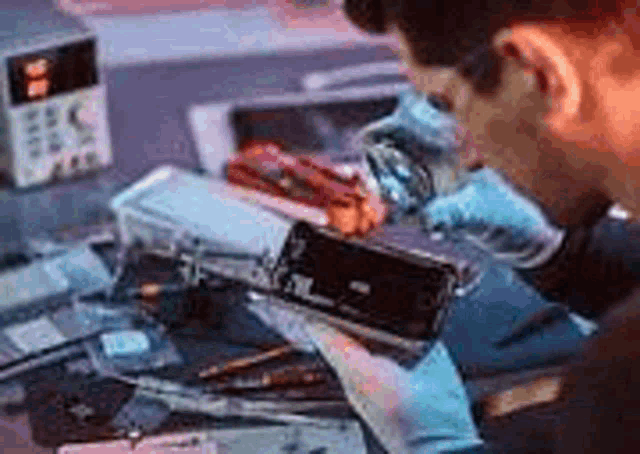 a man is repairing a cell phone in a lab .