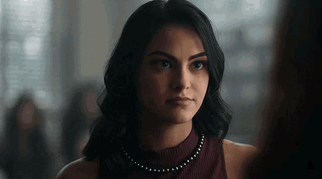 a close up of a woman wearing a turtleneck and a necklace