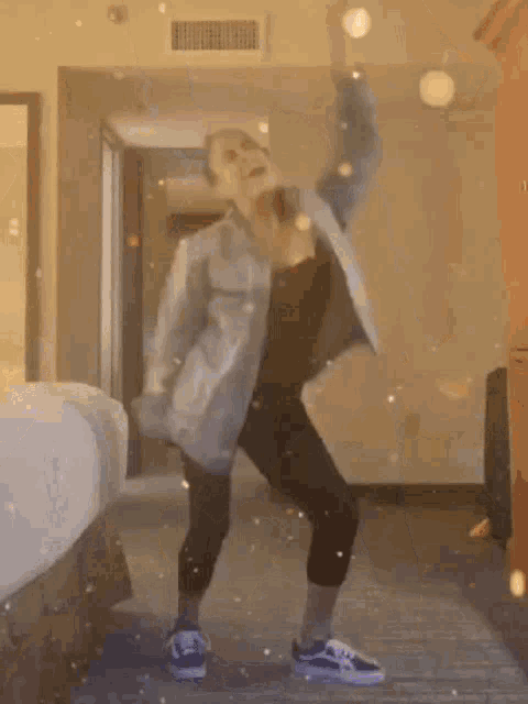 a woman is dancing in a hotel room while holding a balloon in her hand .