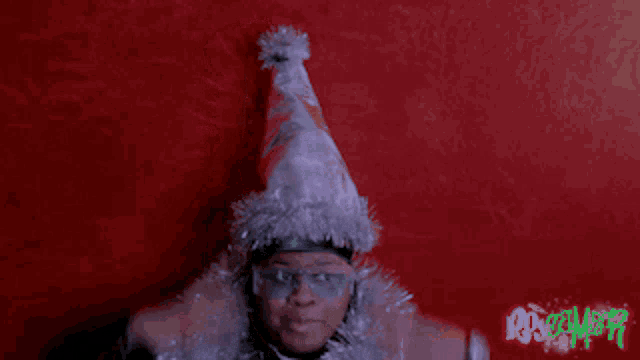 a person wearing a santa hat and glasses is smiling in front of a red wall