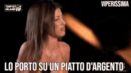 a woman in a bikini is standing in front of a fire and a sign that says temptation island vip .