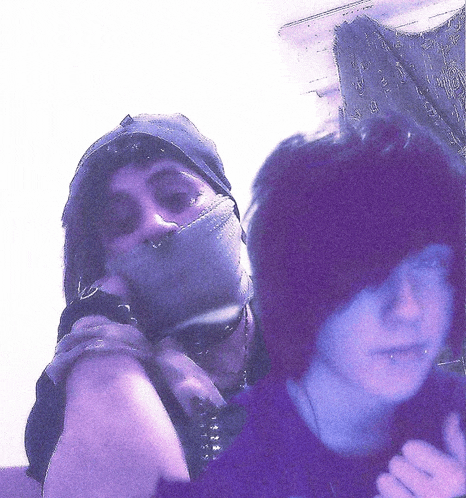 a man with a hat on his head is standing next to a woman with purple hair