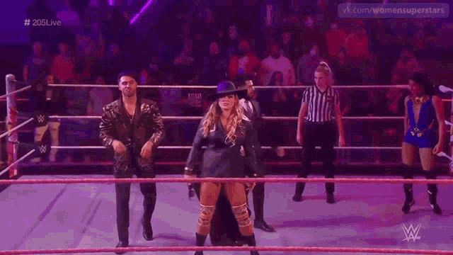 a woman in a hat is standing in a wrestling ring next to a man .