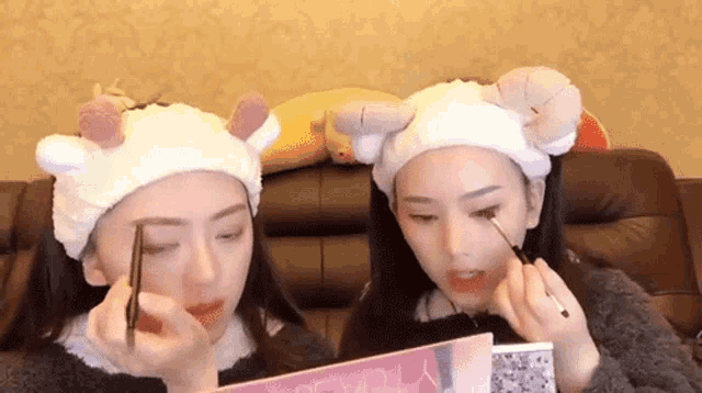 two women wearing headbands are applying makeup on their faces