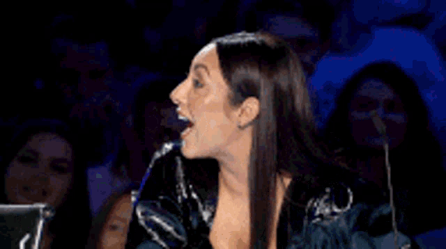 a woman is laughing while sitting in front of a microphone .