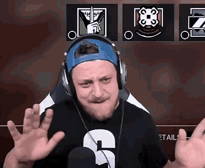 a man wearing headphones and a hat is making a funny face while sitting in a chair .