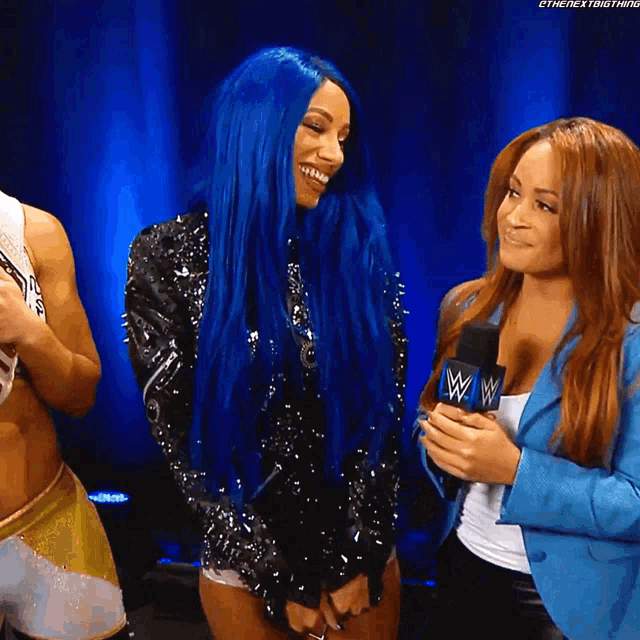 a woman with blue hair is smiling while holding a microphone with the letters w on it