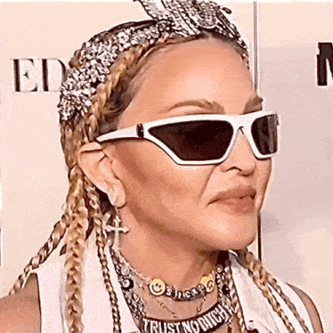 woman wearing sunglasses and a necklace that says trust nobody
