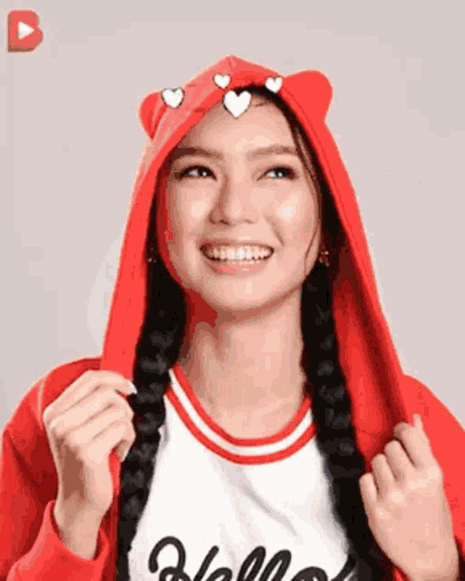 a woman wearing a red hoodie with hearts on it is smiling .