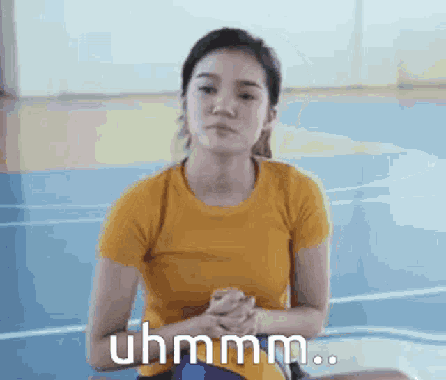 a woman in a yellow shirt is sitting on the floor with her hands folded and the words uhmm .