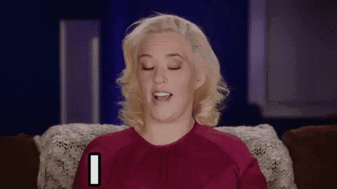 a woman in a red shirt is sitting on a couch with her eyes closed and making a face .