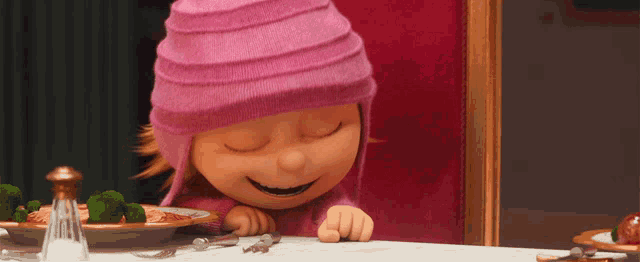 a girl in a pink hat sits at a table