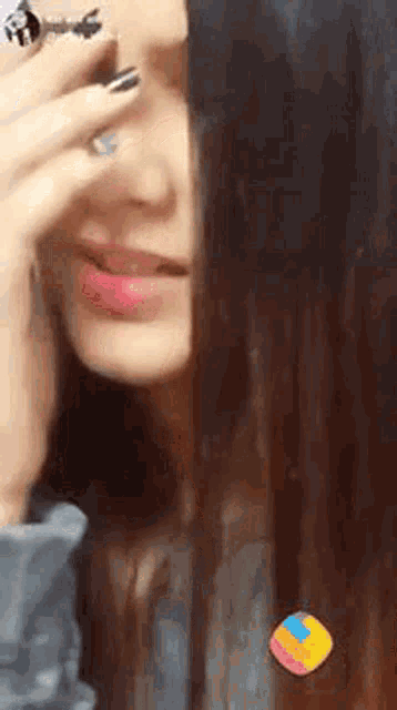a woman is covering her face with her hand while wearing a ring .