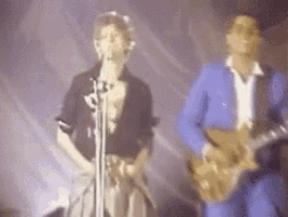a man singing into a microphone and another man playing a guitar