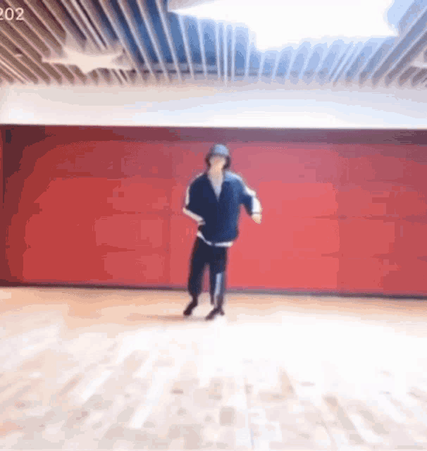 a person is dancing in a dance studio with a red wall behind them .