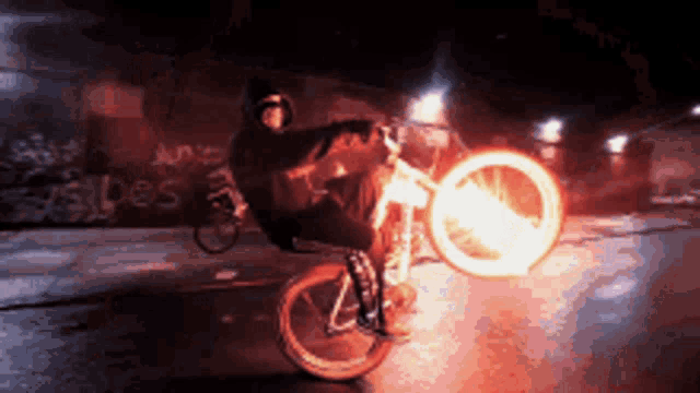 a person is doing a wheelie on a bike with a flame coming out of the wheel