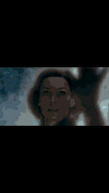 a close up of a woman 's face with a cloudy sky behind her