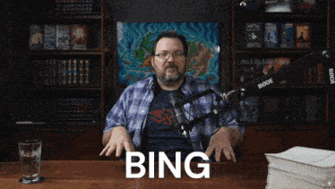 a man sitting in front of a microphone with the word bing on the table