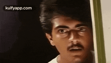 a man with a mustache is peeking out of a door .