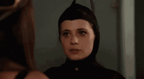 a woman in a batman costume is standing in front of a mirror .