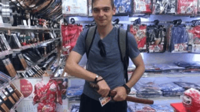 a man is holding a sword in front of a wall that says made in japan
