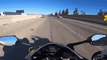 a person is riding a motorcycle on a highway with a yellow sign that says ' yield ' on it