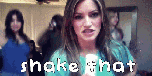 a woman in a blue shirt is holding a remote control with the words shake that above her