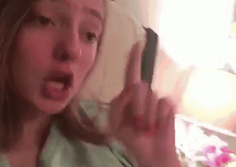 a woman is giving the middle finger to the camera while sticking her tongue out .