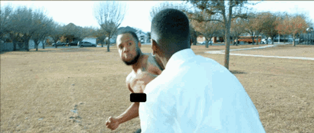 a man in a white shirt is standing next to a shirtless man in a white shirt