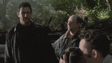 three men are standing in a forest and one of them says " yeah "
