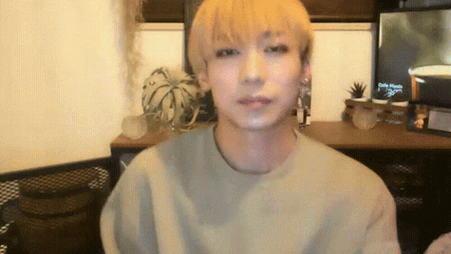 a man with blonde hair looks at the camera in front of a tv screen that says ' cube ' on it
