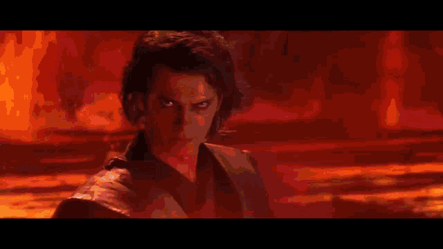 a man is holding a lightsaber in a firey landscape