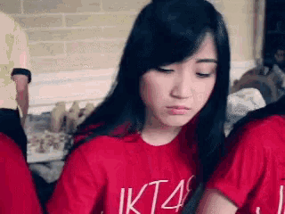 a woman wearing a red shirt that says jkt48