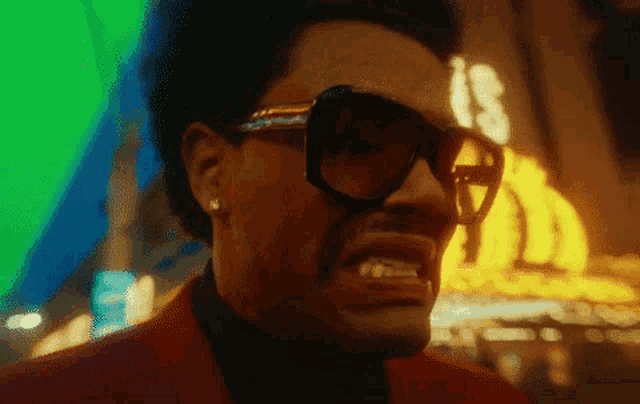 a man wearing sunglasses and a red suit is making a face .
