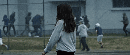a woman in a white shirt is standing in front of a group of people running in the rain .
