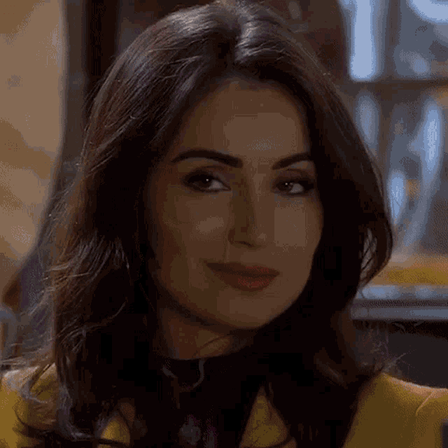 a close up of a woman 's face wearing a yellow jacket and smiling .
