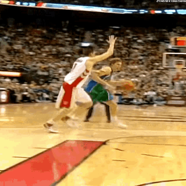 a basketball player dribbles the ball while another player tries to block his shot