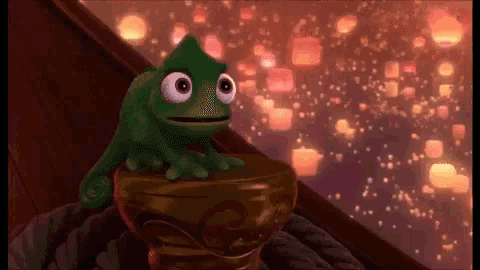 a green frog is sitting on top of a gold object in front of a window .