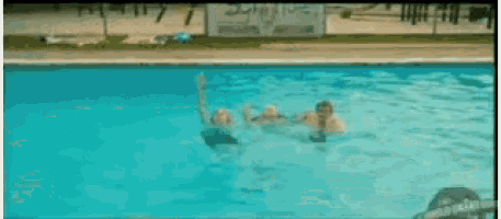 a group of people are swimming in a pool with a sign in the background that says ' swimming '