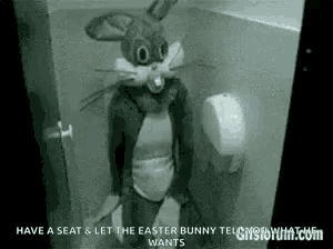 a person dressed as an easter bunny is sitting in a bathroom .