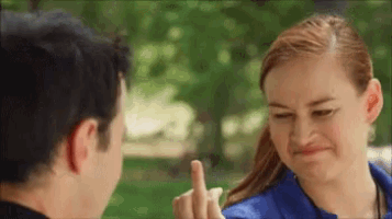 a man and a woman are looking at each other and the woman is giving the middle finger .
