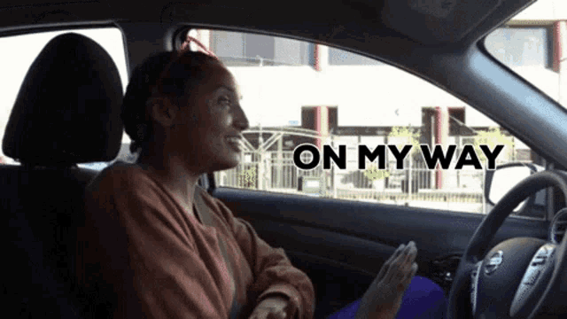 a woman is sitting in a car with the words on my way written above her