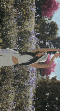 a woman is standing in a field of purple flowers with her arms outstretched